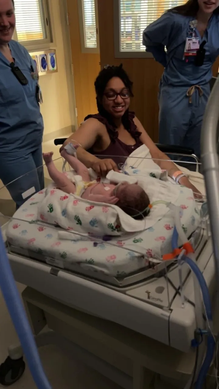 A newborn swaddled in a hospital bassinet